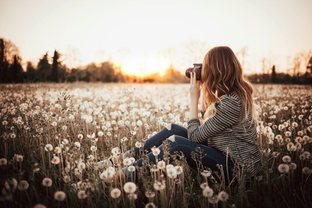 woman photographer taking pictures at sunset in a field