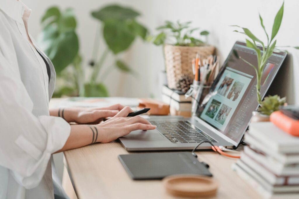 woman typing on a laptop with photos for editing on laptop screen