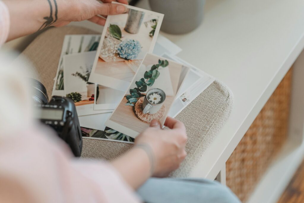 photographer looking through printed out photos with a camera next to her.