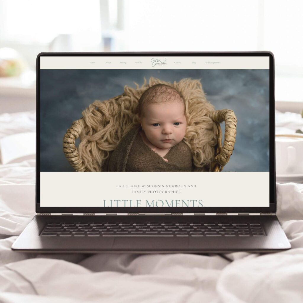 Picture of a laptop open to a newborn photography website. Laptop is sitting on a bed.