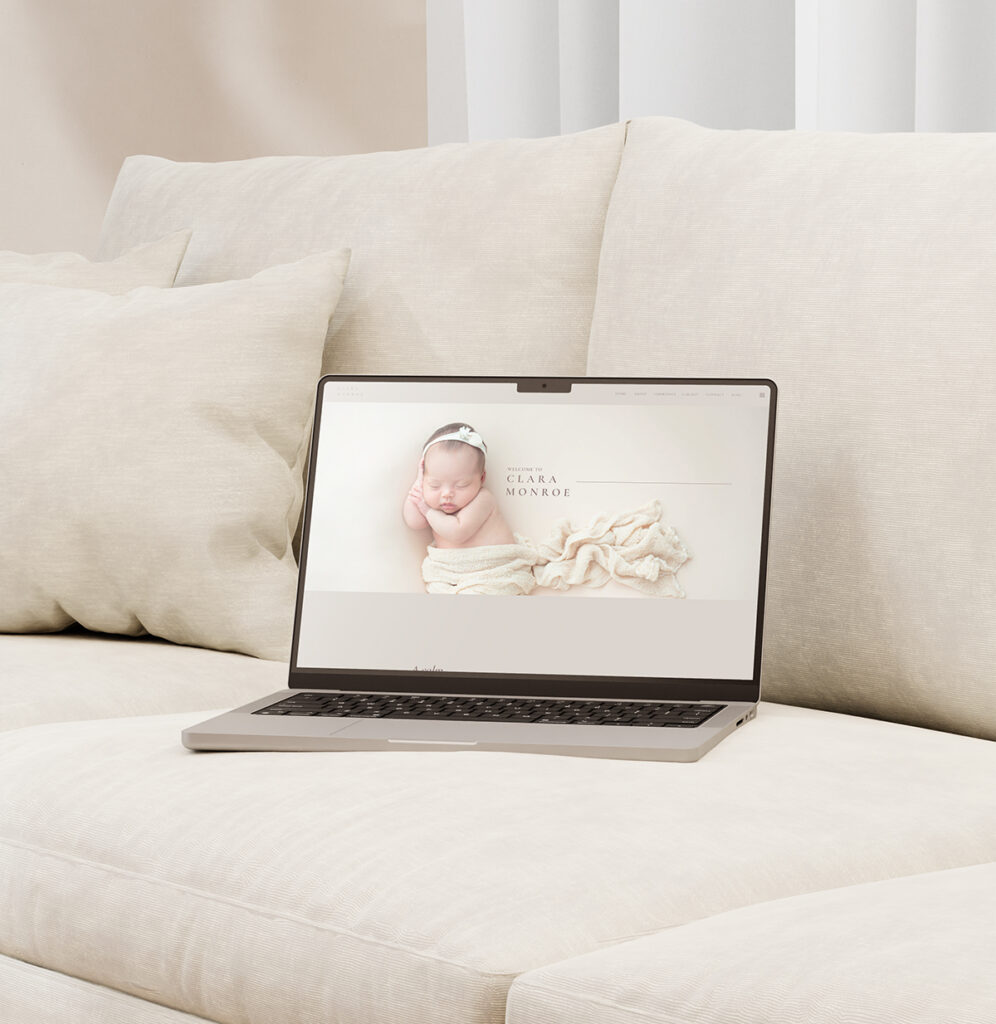 Picture of a laptop on a couch with a newborn photography website on the screen.